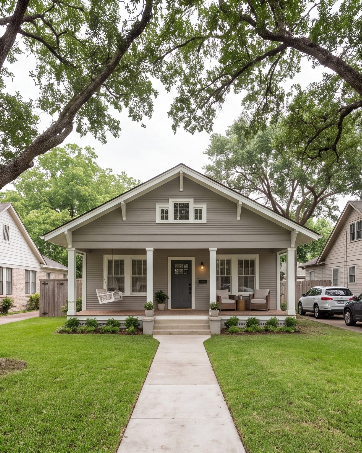 wide street view of a remodeled 1930s Houston bungalow with its original porch, fresh paint, mature trees